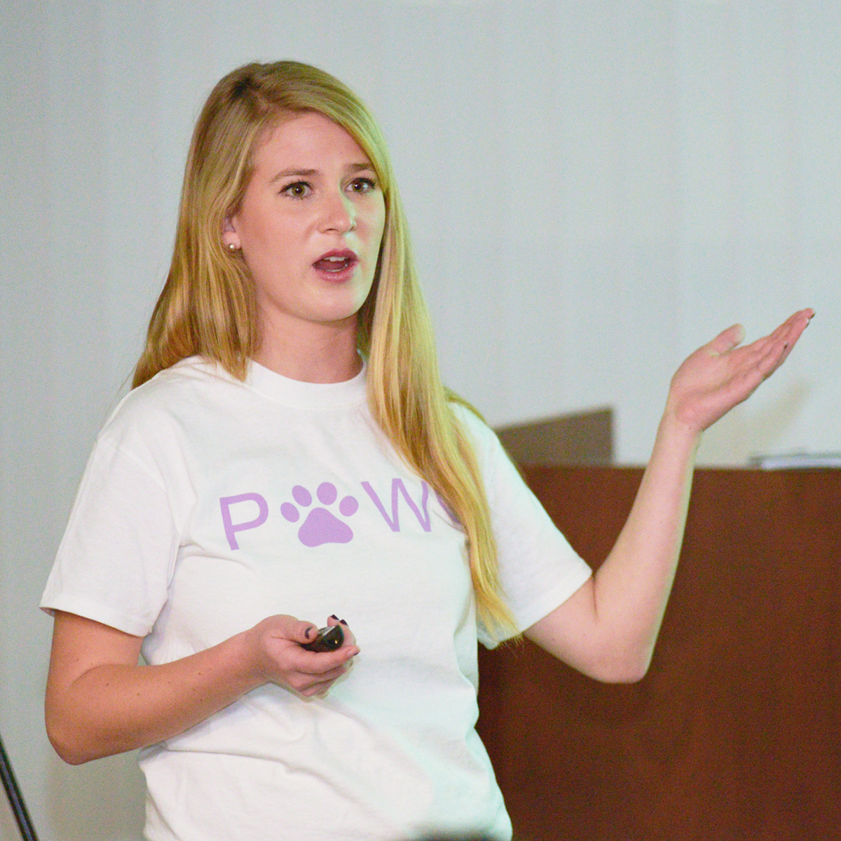A student presenting in a classroom wearing a t-shirt with the 